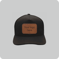 Front view of a BrimCo black 5-panel performance baseball cap featuring a blank, rectangular brown faux leather patch on the front, displayed against a clean light grey background.