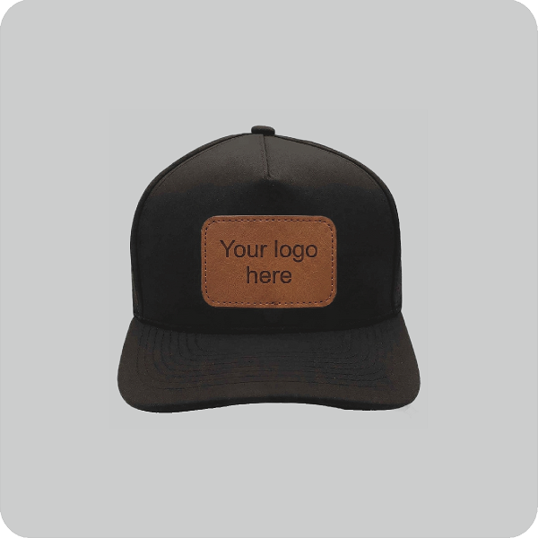 Front view of a BrimCo black 5-panel performance baseball cap featuring a blank, rectangular brown faux leather patch on the front, displayed against a clean light grey background.